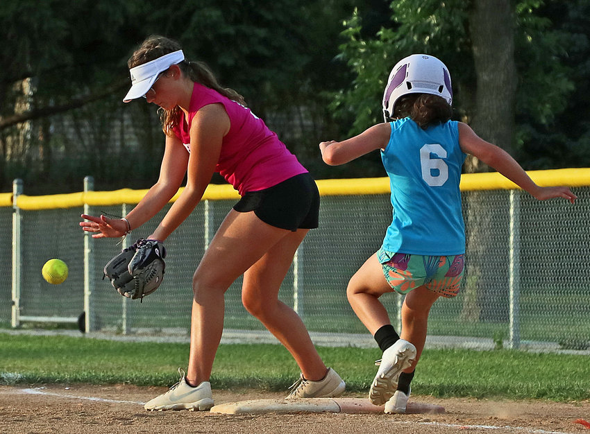 Lauren Whrli of KRW Construction, left, tries to glove the ball as Wendy's Nails' Alexis Kern races to first base June 30 at the Youth Sports Complex.