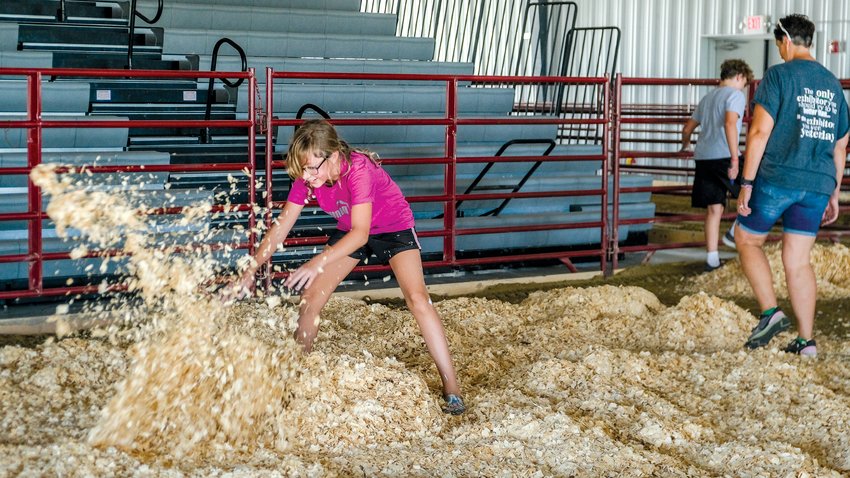 Allie Larsen spreads wood shavings in the Two Rivers Arena to prepare it for livestock shows at this year's Washington County Fair.