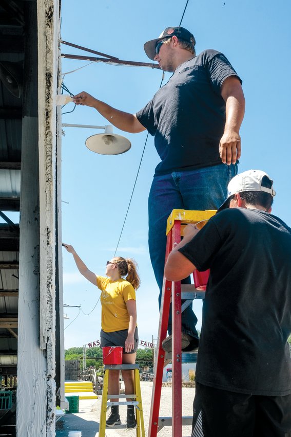 Nora Cloudt, Wyatt Cox and Luke Valasek, from left, paint the front of the sheep barn during the Washington County Fair clean-up day on July 24.