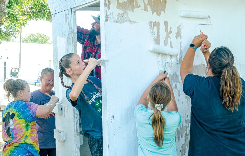 Washington County 4-H leaders and members paint the ticket booth at the Washington County Fairgrounds.