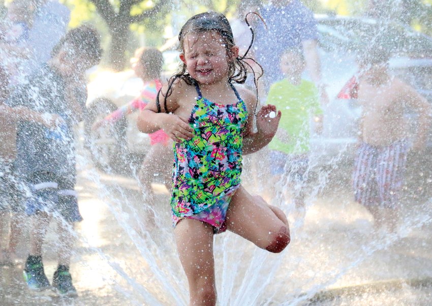 Molly Wattenbach, 4, runs through a sprinkler fed by a firehose near Lions Park on July 21. The Blair Volunteer Fire Department hosted two fire hydrant parties throughout town to both provide fire hydrant training for firefighters and a way for children to cool down from the 90-plus degree temperatures.