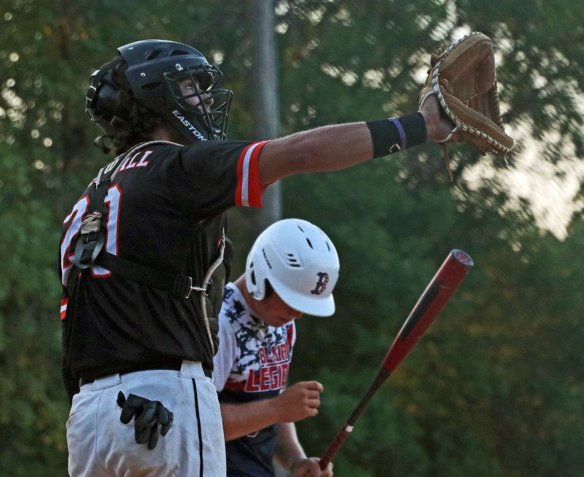 Fort Calhoun catcher Justin Myer, left, puts his glove up for a throw from his dugout Friday during a short delay at Vets Field.