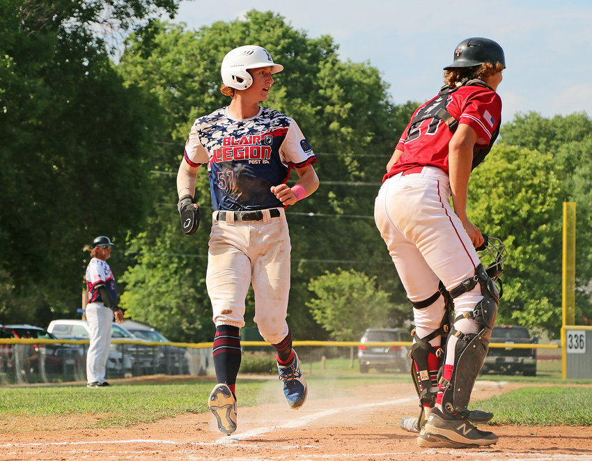 Blair Legion base runner Nate Wachter, middle, scores a run Tuesday at Vets Field.
