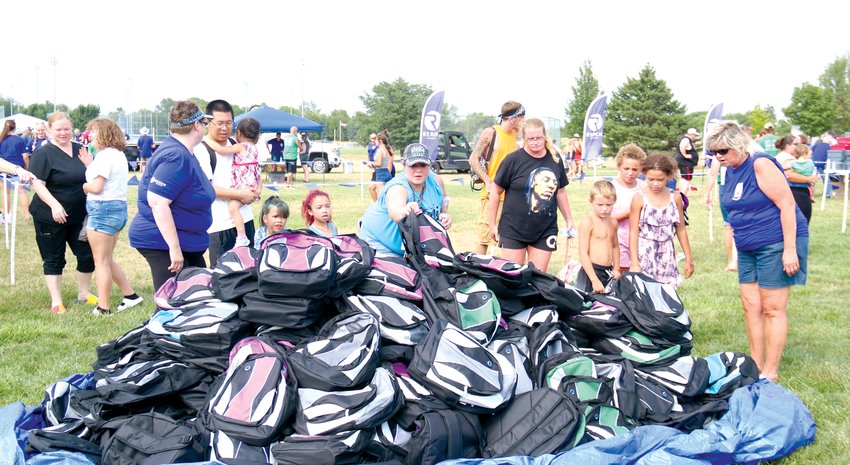 Families look over a pile of backpacks before making their selection at Pack the Park on Aug. 7.