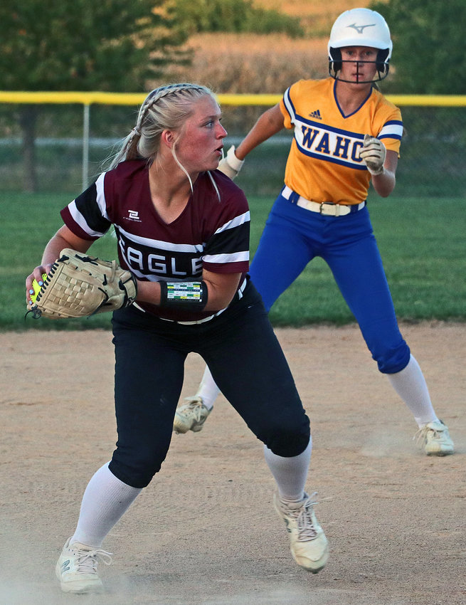 A Wahoo base runner watches as Arlington senior Hannah Stahlecker, left, fields a grounder and throws it to first base for an out Tuesday at Two Rivers Sports Complex.