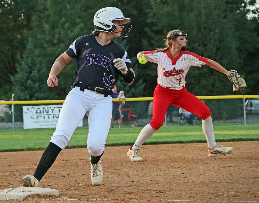 Blair junior Kalli Ulven, left, reaches third base and looks over her shoulder as Wahoo Neumann's Grace Shulz attempts to make a throw to first Monday at the Youth Sports Complex.
