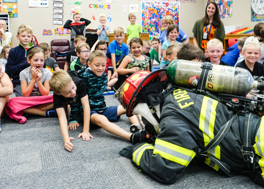 Dressed in fire gear, David McIntosh demonstrates how a fire fighter would search a burning house for fire victims during a Fire Prevention Week presentation at South.