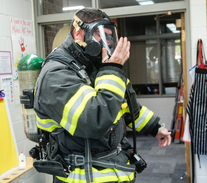 Fire fighter David McIntosh checks his breathing apparatus and face mask.