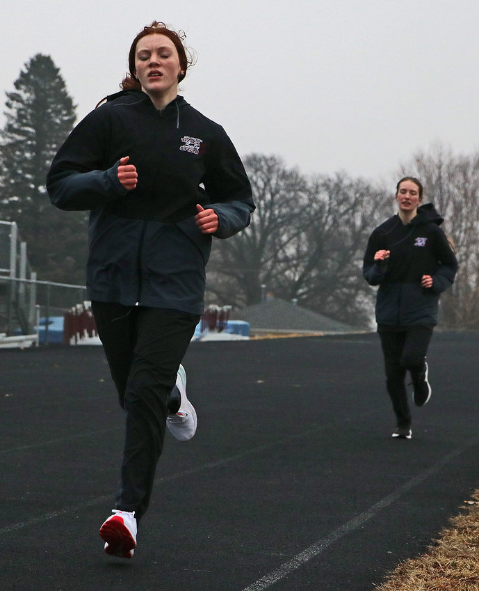 Callee, left, and Paige Shearer run down the track March 8 at Arlington High School.