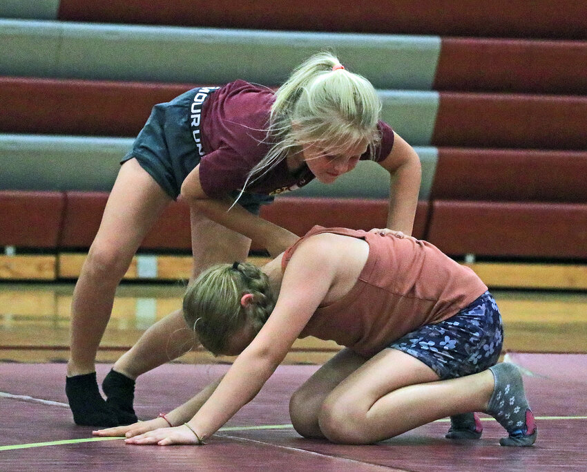 Madelynn Nissen, 8, top, works on her wrestling skills with Carly Sass, 10, on Tuesday at Arlington High School.