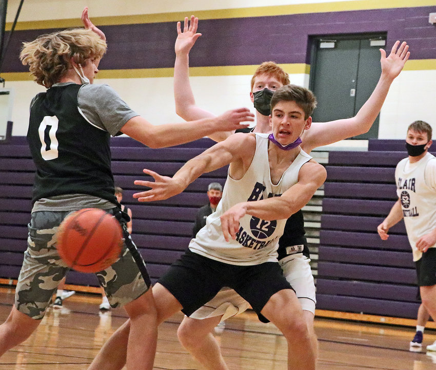 The Bears' Luke Ladwig, middle, passes the ball out from between teammates Kade Ryden, left, and Leo Clarke on Tuesday during practice at Blair High School.