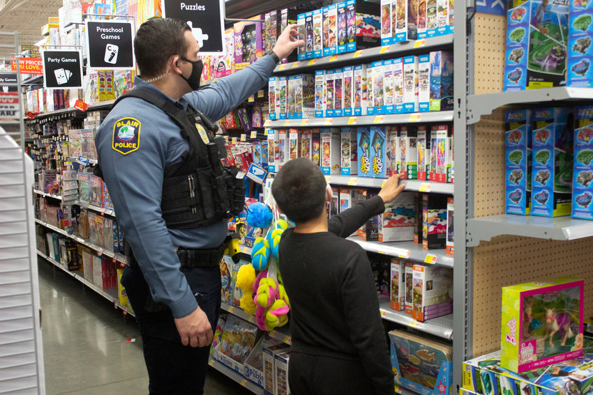Officer Seth Ferryman observes puzzles with Mario Carmona Thursday at Walmart for Blair Police Department's annual Shop with a Cop event.