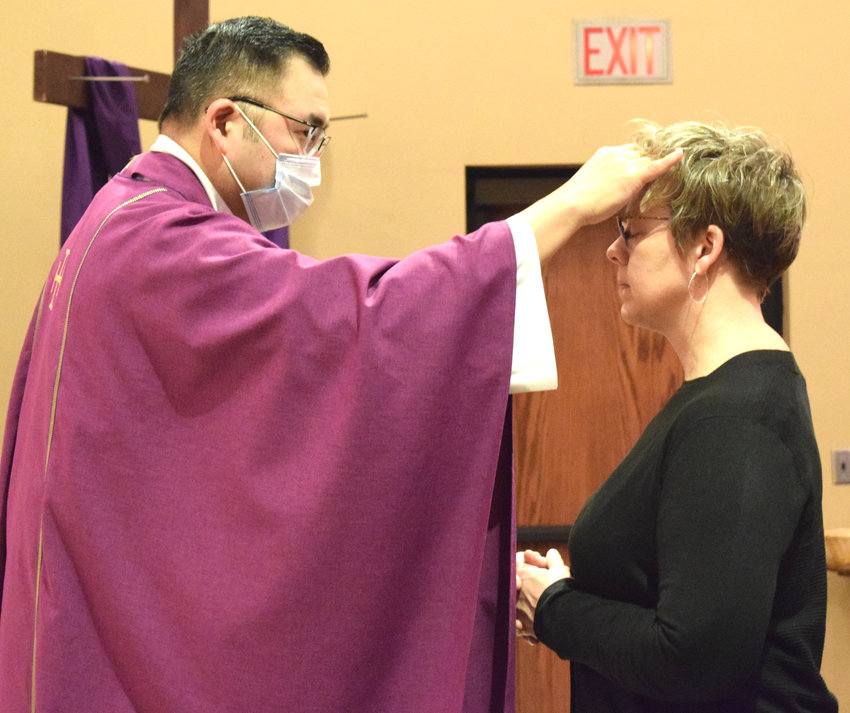 Father Damien Wee, left, places ashes on Beth Holdridge's forehead on Ash Wednesday at St. Francis Borgia Catholic Church in Blair.