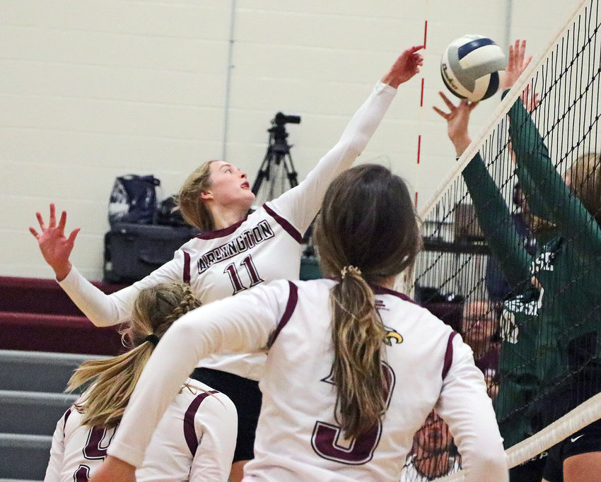 Eagles senior Chase Andersen, facing, hits the ball through a Syracuse block as Lizzie Meyer, left, and Janessa Wakefield watch Tuesday at Arlington High School.