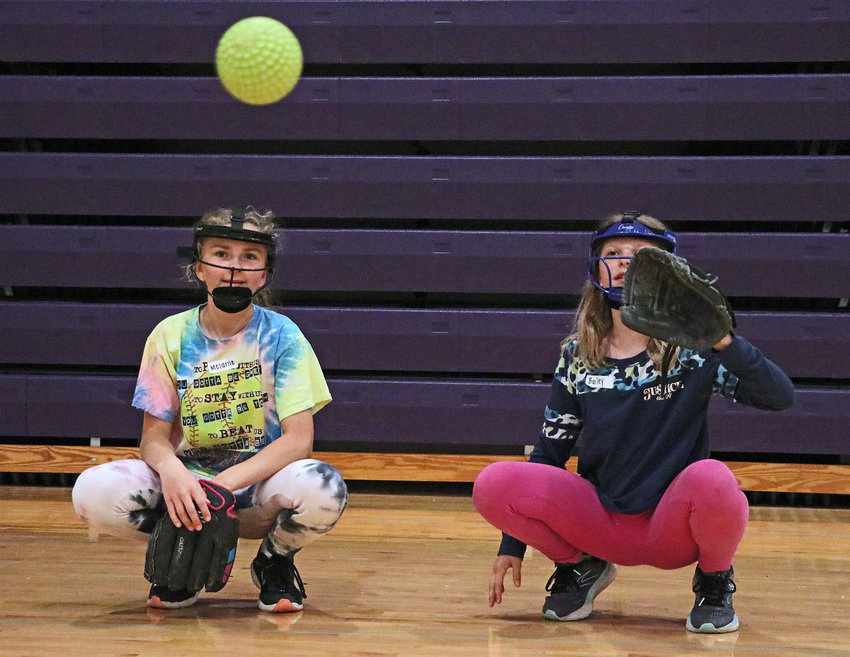 Melanie Korth, 10, left, and Bailey Batenhorst, 11, work on their skills behind the plate Wednesday during the Blair Softball Youth Camp at BHS.