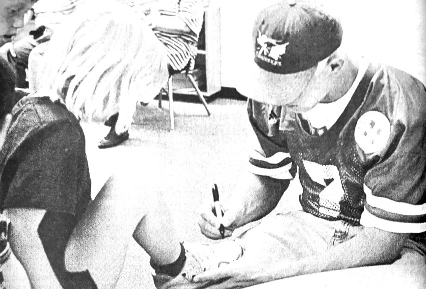 Nebraska quarterback Scott Frost signs the shoe of Kelsey Shrum during a 1997 visit to a Blair elementary school. Frost is the current head football coach of the Cornhuskers.