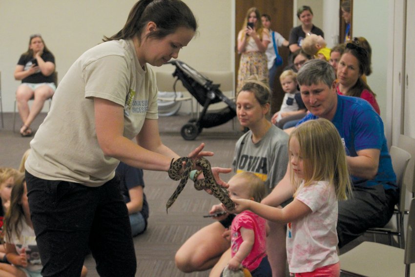 Papio-Missouri River Natural Resources District natural resource educator Kaylyn Kelley lets four-year-old Averie Wehner pet a fox snake. Kelley was on hand at the Blair Public Library and Technology Center with a host of critters for an Animal Adaptations presentation on June 7 to celebrate the beginning of the Summer Reading program.