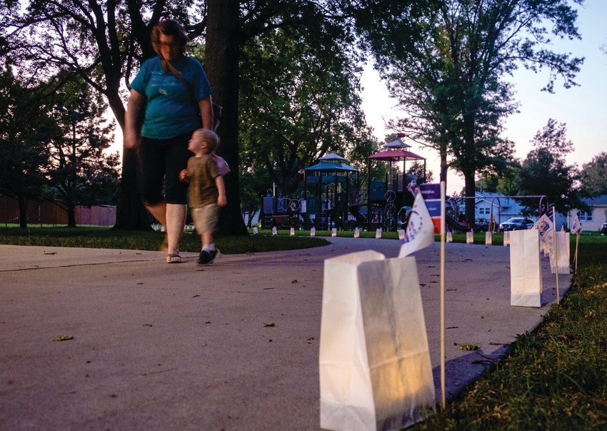 Cindy Breitkreutz and grandson Riley Wethington walk along the luminary path at dusk at Lions Park at last year's Relay for Life. The Washington County Relay for Life returns to Lion's Park on June 25.