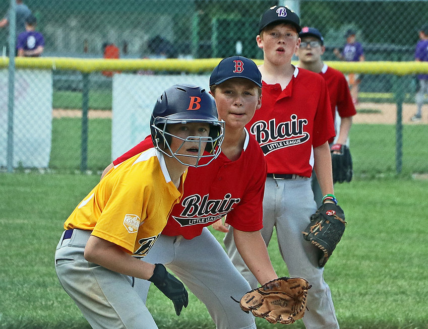 Blair Little League A's base runner Donovan Maggio, left, eyes home plate as Red Sox Carter Ross, from left, Sean Casey and Weston Sears back up the play Tuesday during Majors Division postseason play at Wederquist Field.
