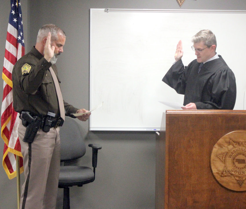 Deputy Jeff Baker is sworn in by Judge Francis W Barron III Wednesday afternoon at the Washington County Sheriff's Office. Baker is a former Omaha police officer, where he worked for 29 years.