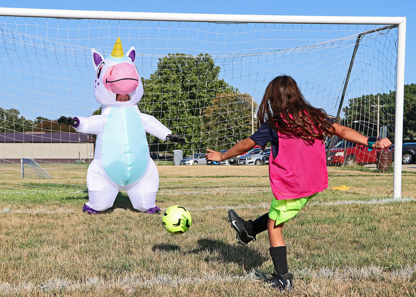 Olivia Whitwer, 7, fires a shot past a unicorn July 27 at the Blair High School youth camp. BHS keeper Kaitlyn Johnson dressed up for the job in goal.