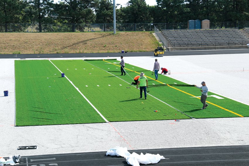 Workers secure a section of the new field turf at Krantz Field to the surface on July 29.