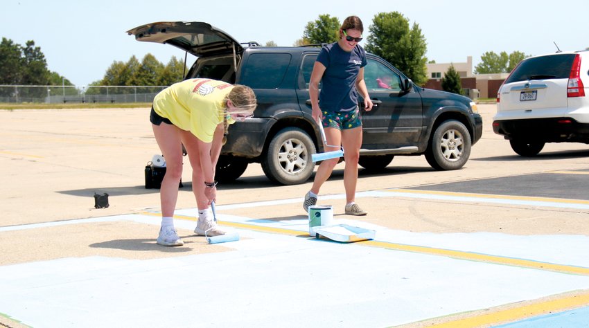 Ellia Klanderud, left, and Ashley Behnk paint their parking spaces at Blair High School on Aug. 2.