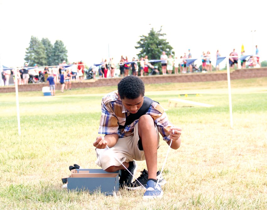 Savion Austin, 14, tries on a pair of shoes at Reach Church's Pack the Park backpack and shoe giveaway at the Youth Sports Complex in Blair on Aug. 7.