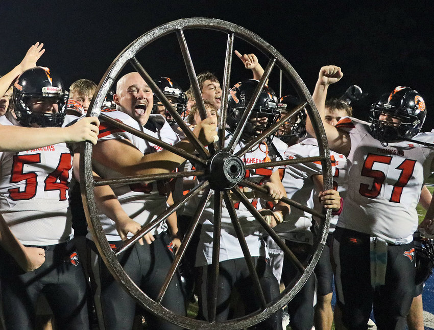 The Fort Calhoun High School football team celebrates with their wagon wheel trophy Saturday at the conclusion of the first Pioneer Bowl at Peru State College. The Pioneers beat Nebraska City 27-12.