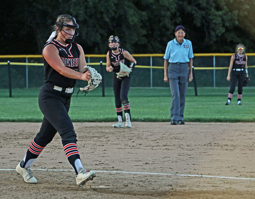 The Pioneers' Anna Taylor, left, steps into a pitch as Izzy Greenough, from left, the umpire and Sammie Ladwig watch Tuesday in Fort Calhoun.