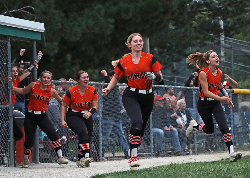 The Pioneers race out of the dugout to celebrate Kaitlyn Welchert's second home run against Arlington on Thursday in Fort Calhoun.