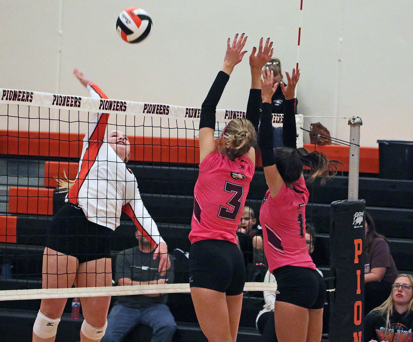 The Pioneers' Raegen Wells, left, spikes the ball as Arlington's Macy Wolf, middle, and Emme Timm attempt to block it Monday at Fort Calhoun High School.
