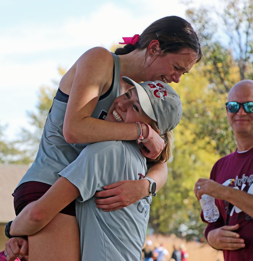 Arlington coach Michaela Curran picks up two-time Eagles state champion Keelianne Green on Friday during the NSAA State Cross-Country Championships at Kearney Country Club.