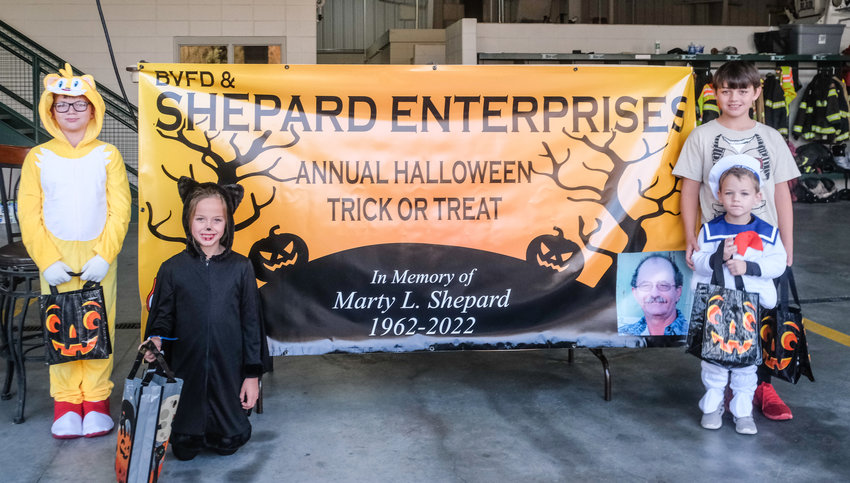 Caden Saunders, Giana Slandered, Noah and Hudson Saunders, from left, stand with their treats in front of sign dedicated to Marty Shepard, who enjoyed distributing candy to trick-or-treaters at the Blair north fire station. Shepard passed away in September but the fire department continued the tradition in his honor.