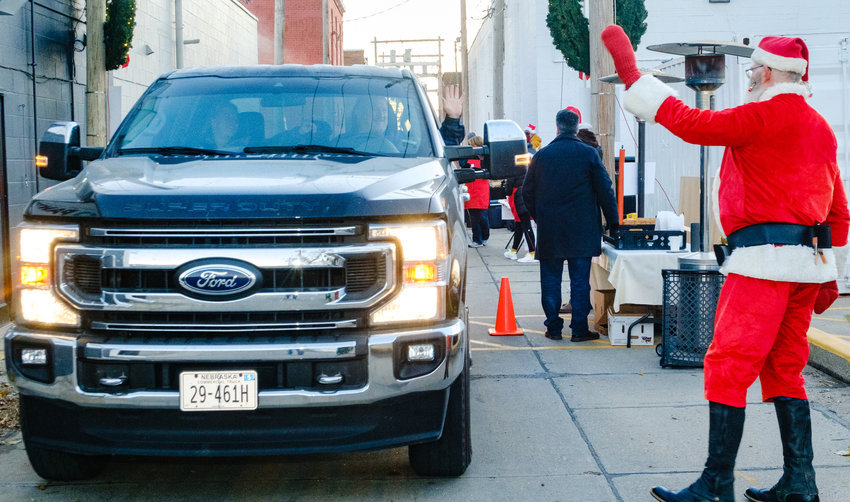 Santa (Craig Shogren) waves to vehicles lined up to take part in the Christmas for the Coat drive up fundraiser last year. This year's edition returns to the alley behind Joseph's Coat on Dec. 7 from 6:30 to 9 a.m.