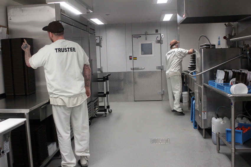 Two trustees work in the Washington County Jail's kitchen Wednesday morning. The trustee program is available for inmates who want to help out around the jail, where they perform tasks such as washing trays from meals or doing laundry.