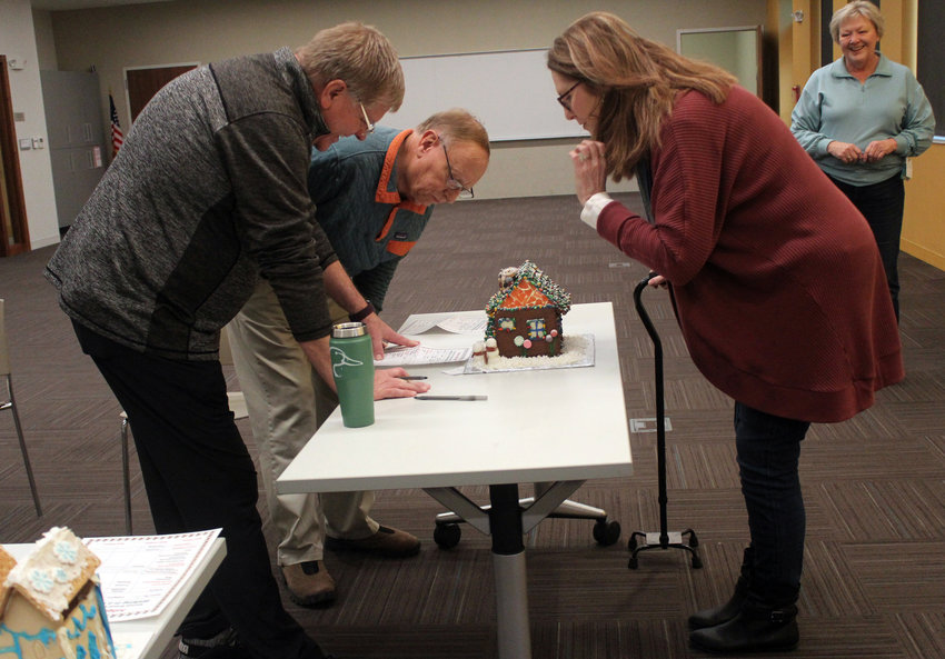 From left, Pastors Mark Degner, Rod Hansen and Gina Gile were the judges chosen for the Blair Public Library and Technology Center's second annual gingerbread house contest. Margaret Hanson, pictured in back, alongside Wendy Lukert set up the tables of creations.