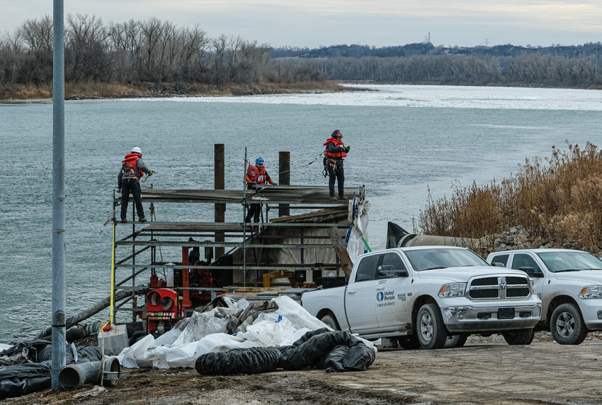 Crews remove enclosures protecting auxiliary pumps on the Missouri River in Blair on Dec. 28. The pumps were removed because of rising river levels from an ice jam, which can be seen in the background. The pumps will be replaced for standby use in case the ice jam south of Blair lets up and water levels once again require auxiliary pumping.