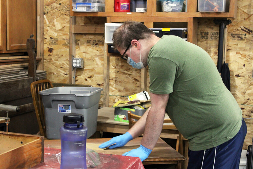 Evan Fowler of Blair works on sanding a dresser at the Roots to Wings Garage Tuesday afternoon.