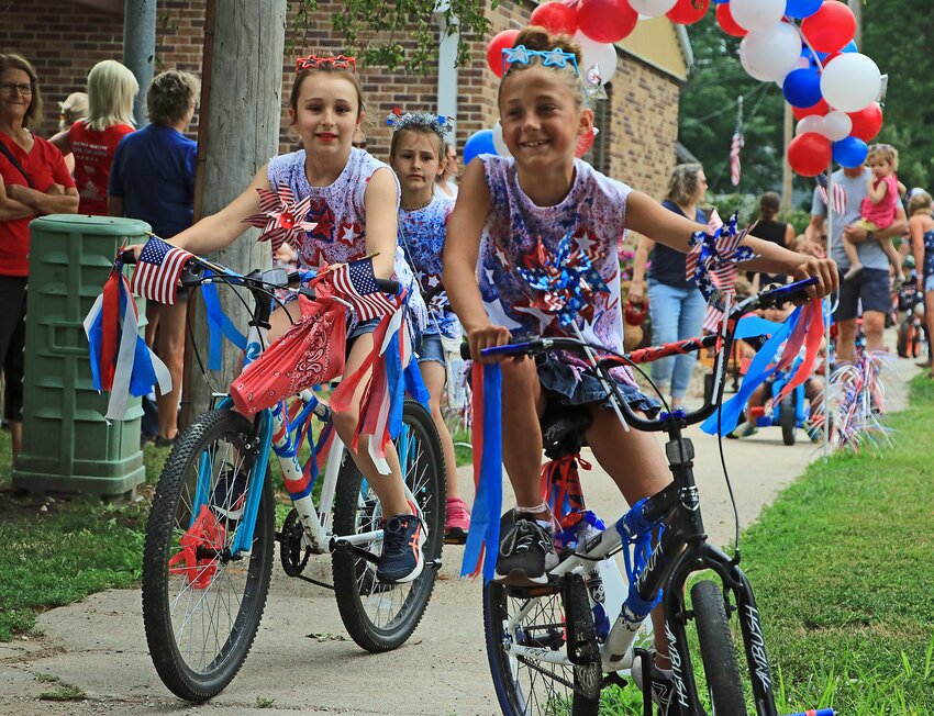 Molley Petersen, from left, Lydia Petersen and Jayla Dowty ride bikes Saturday during the Summer Sizzle Kiddie Parade in Arlington..