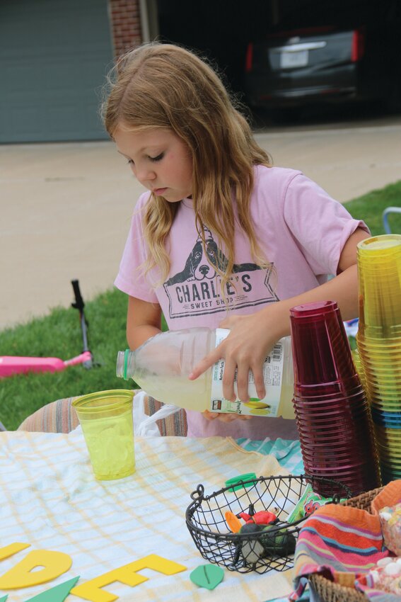 Kennady Gregory (12) pours a cup of lemonade for a customer.