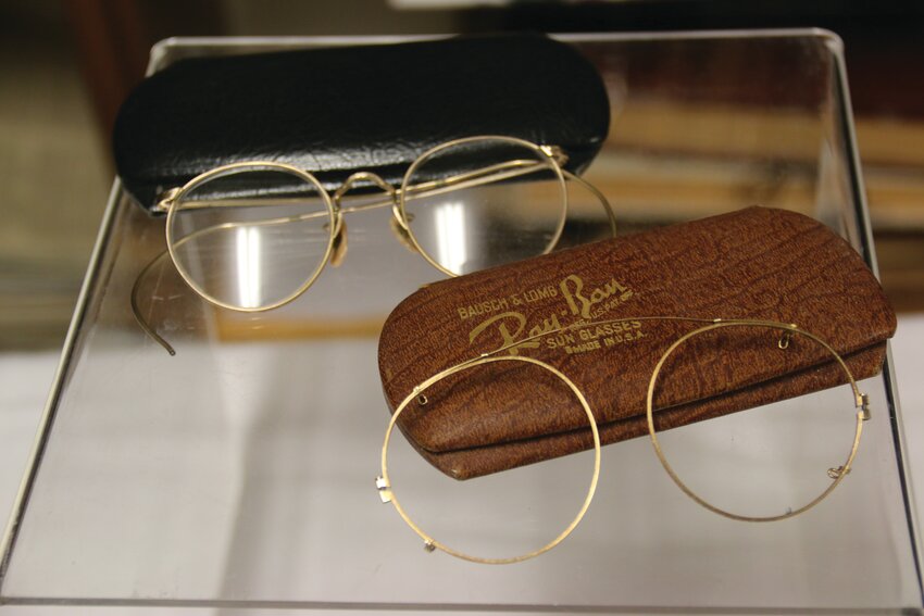 A pair of wire rimmed glasses with temples that curve around the ears (top) and the frame to a pair of Ray-Ban sunglasses (bottom).