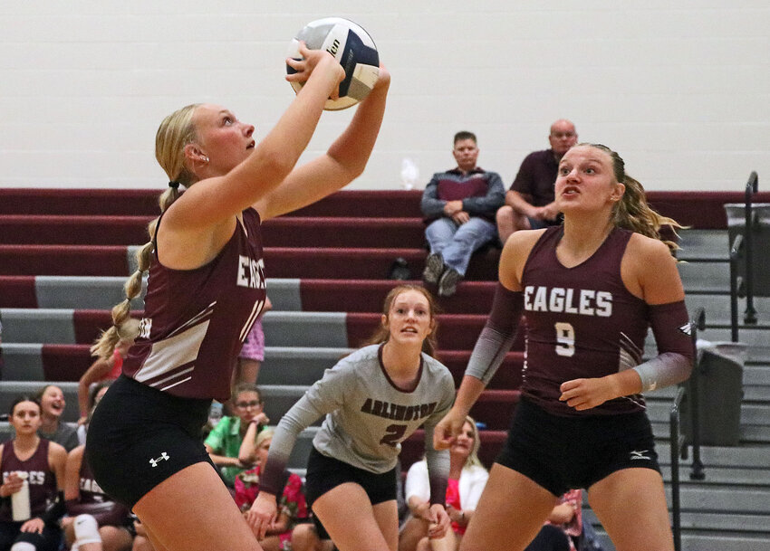 The Eagles' Austyn Flesner, left, makes a play on the ball as Callee Shearer, middle, and Lizzie Meyer watch Thursday at Arlington High School.