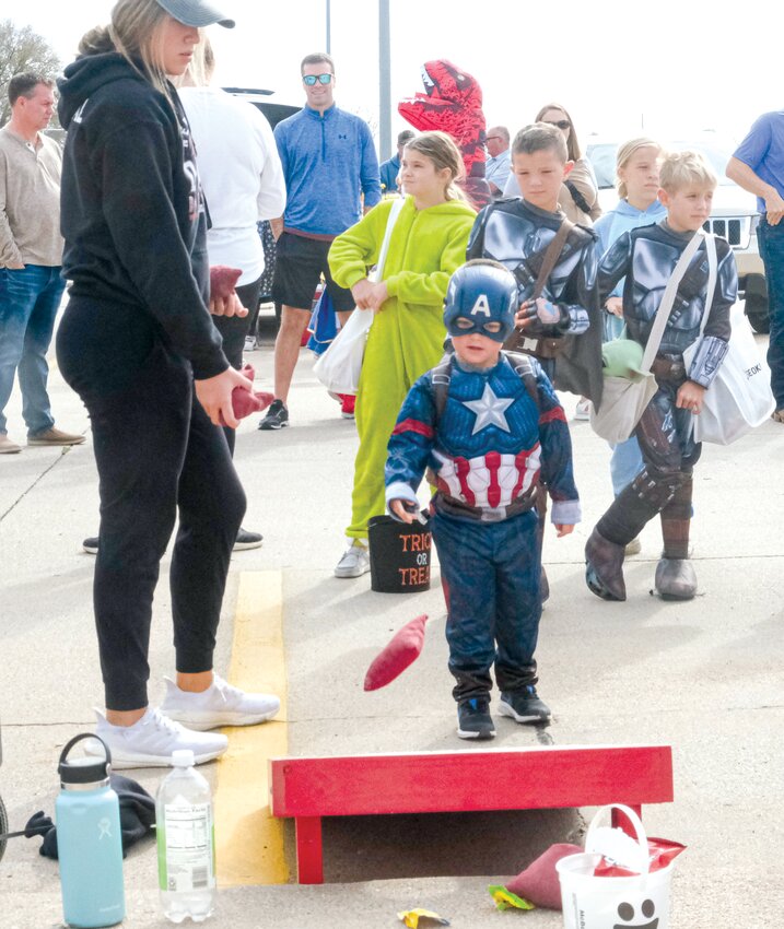 Captain America throws a bag at the corn hole toss sponsored by the Arlington Girls Basketball program last year on Halloween.