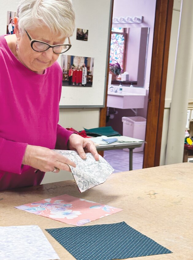Carolyn Stengel helps layout the quilt blocks and carefully arranges them to be sewn.