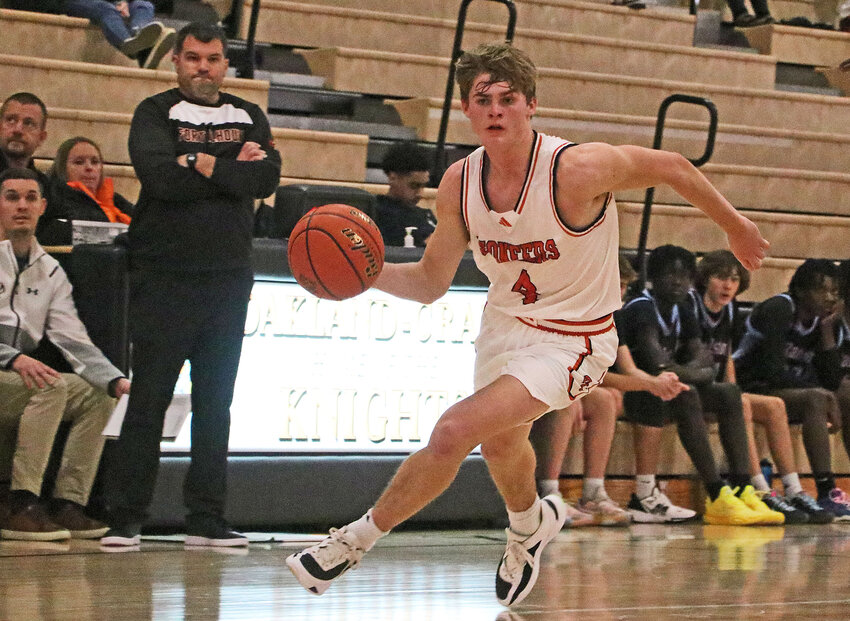 Fort Calhoun senior Grayson Bouwman dribbles up the floor as coach TJ O'Connor, standing left, watches Monday against Ralston at Oakland-Craig.