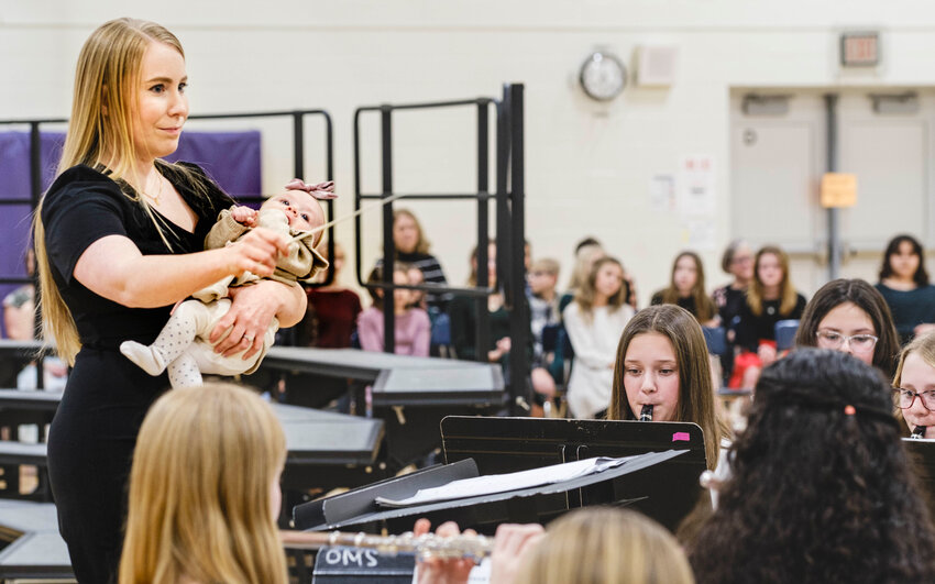OBMS Band director Courtney Reznicek cradles daughter Leah Grace in one arm while she directs the band with the other. &ldquo;It has been a dream of mine forever to share the podium with my baby! I love the idea of my kids growing up 'in a band room' surrounded by music and I wanted to have this special moment with my first born!&rdquo; she said.
