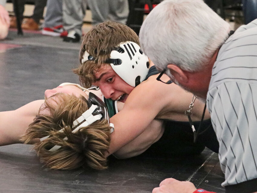 Fort Calhoun's Landon Bernasek, middle, pins his opponent in front of the referee Saturday at Douglas County West.