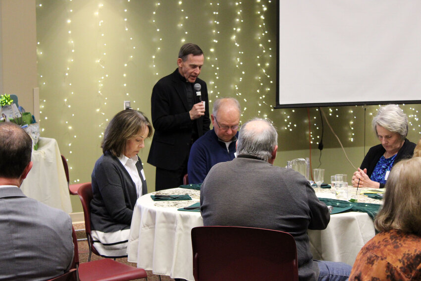 Fr. Michael Gutgsell, Fr. Stephen Gutgsell's brother, leads the group in a prayer before dinner is served Saturday evening at St. Francis Borgia Catholic Church for the St. John Paul II Classical Academy scholarship fundraiser. The scholarship is being named after Stephen Gutgsell, who was a large supporter of the school and was going to be the school's Latin teacher.