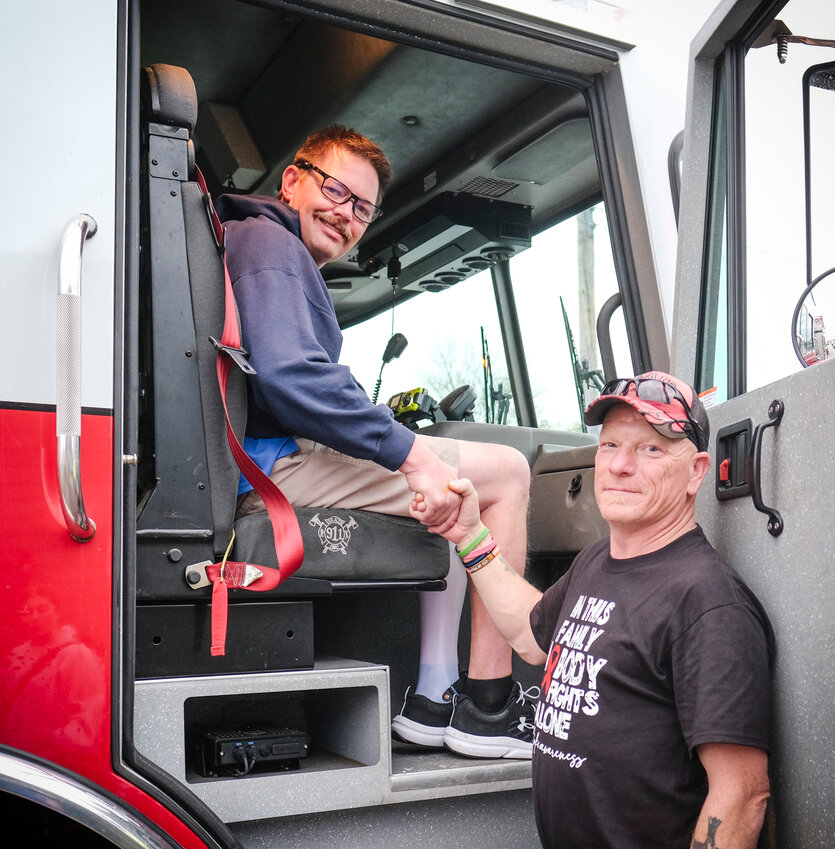 Randy Backman seated in a Kennard Fire Truck shakes hands with Blair Fire Fie Chief Joe Leonard Saturday evening. The Kennard Fire Department gave  Backman and some of his care workers a quick spin through the streets of Kennard.